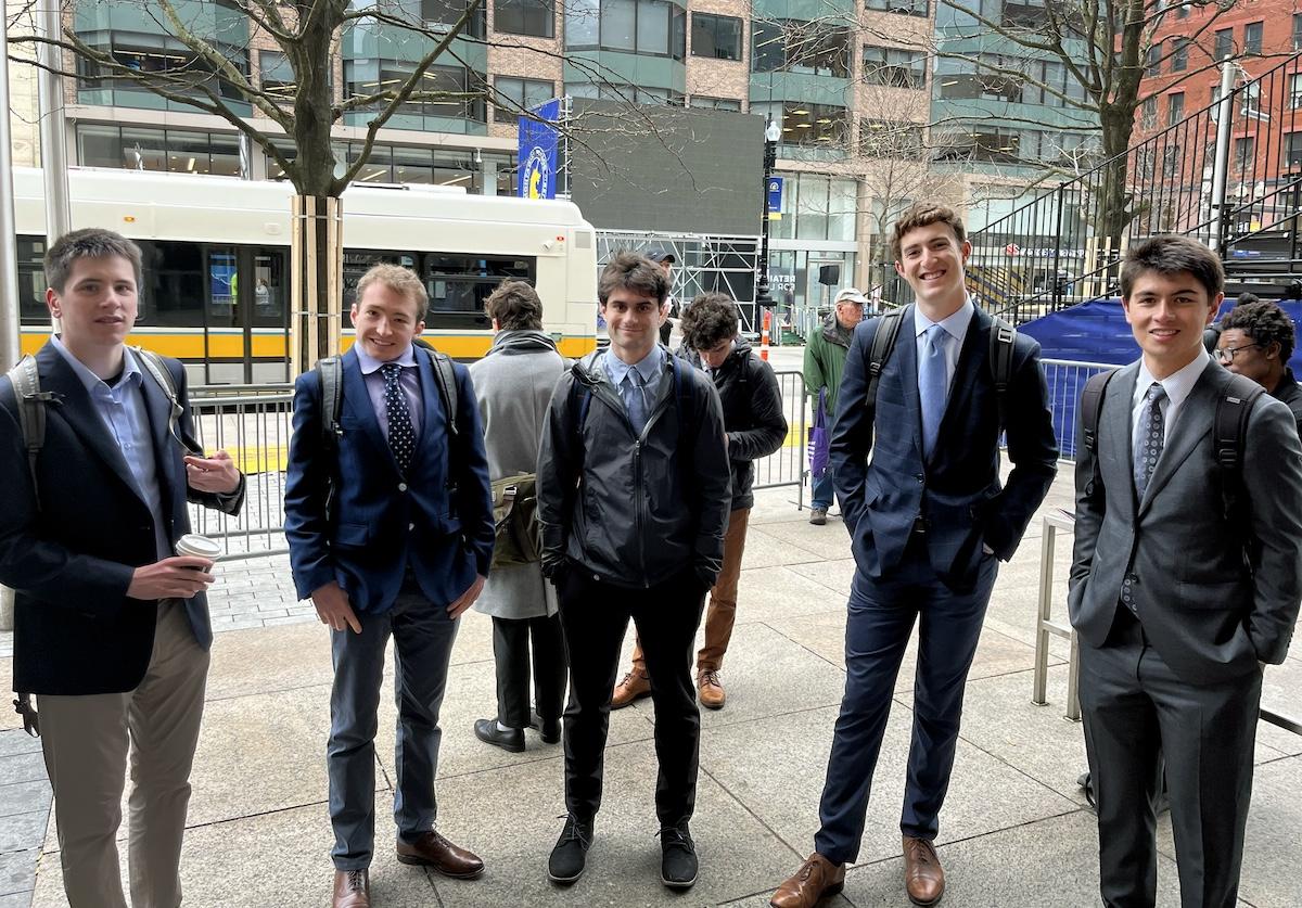 5 college students wearing business suits and backpacks on a city street