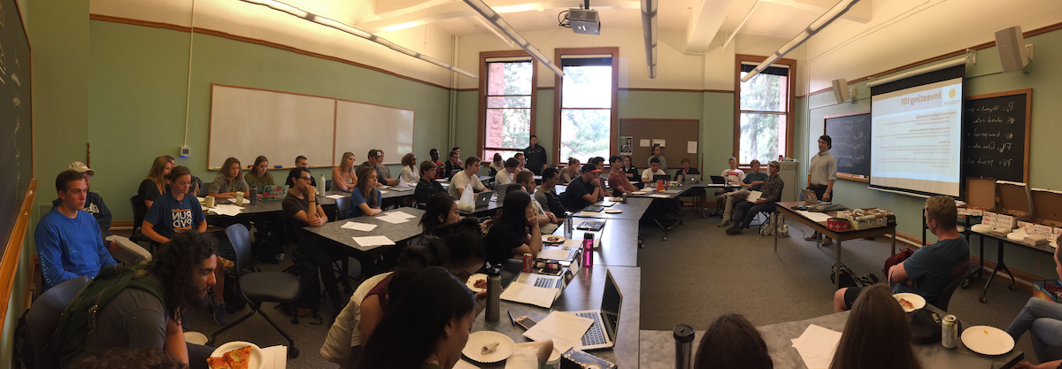 Dozens of college students in a classroom sitting and listening to a lecture on investing