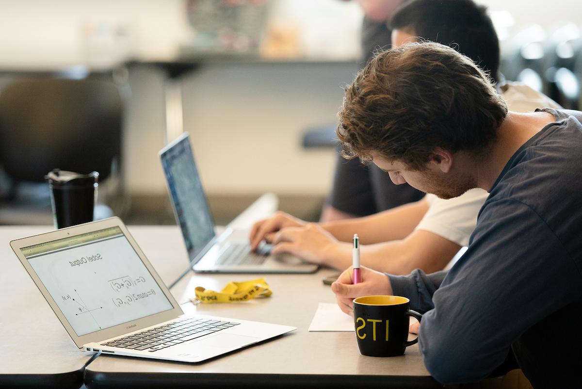 A college student working at a desk with a laptop on a Sobel Output equation 